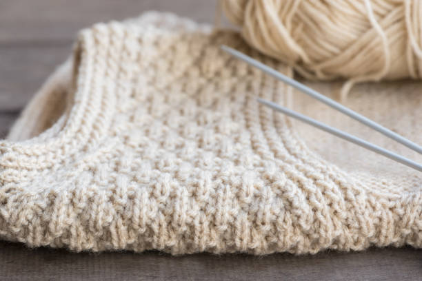 Knitted sweater with knitting needles and yarn. stock photo