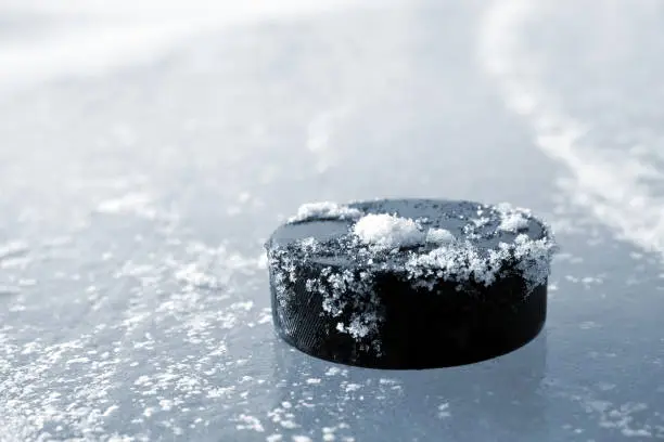 Hockey puck lying on a ice rink.