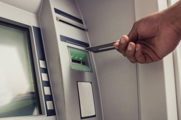 Close up of unrecognizable person with credit card on ATM. Close up of man's hand about to put a credit card into a cash machine. atm photos stock pictures, royalty-free photos & images