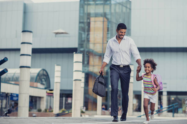 Hurry up baby, we are going late to school! Happy African American father and his small daughter holding hands and running outdoors. moving activity stock pictures, royalty-free photos & images