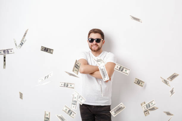 istock young happy man with a beard in white shirt standing under money 644983296