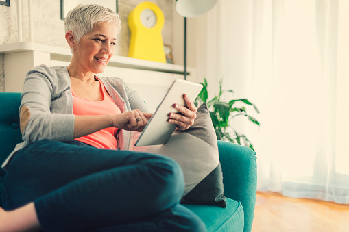 Mature woman using digital tablet at home