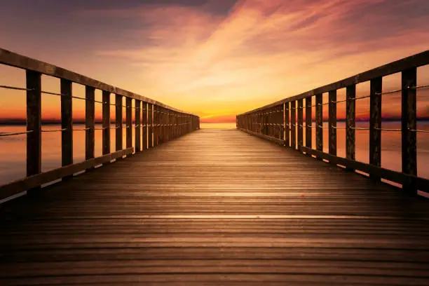 Image of wooden pier with colorful sky on the beach at sunset time