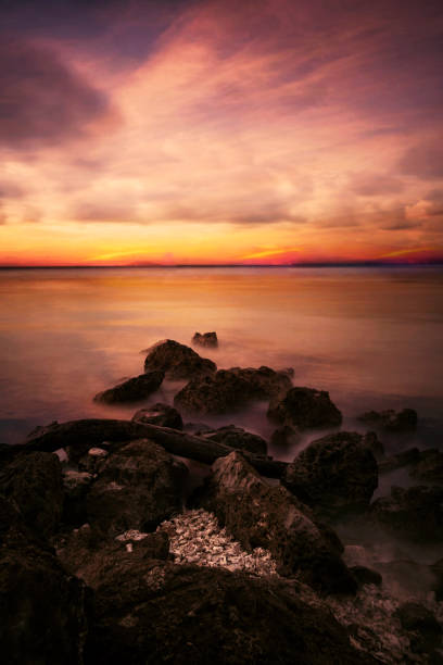 istock Colorful sunset with rocks on beach 644997386