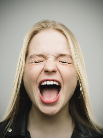 Mujer emocionada gritando contra el fondo gris photo
