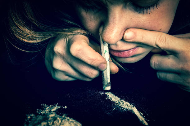 junkie kobieta parskanie proszku kokainy z walcowane banknot - snorting zdjęcia i obrazy z banku zdjęć