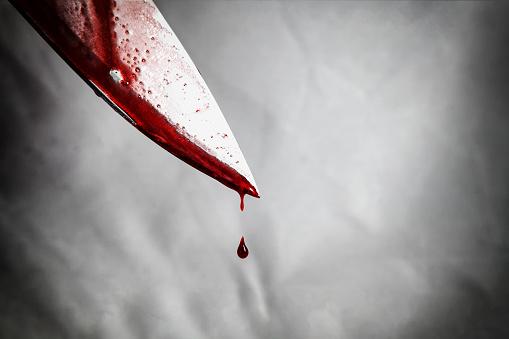 primer plano de hombre que sostiene el cuchillo manchado con sangre y todavía goteo. photo
