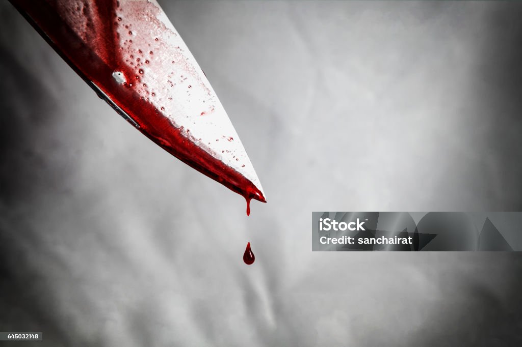 close-up of man holding knife smeared with blood and still dripping. Murder Stock Photo