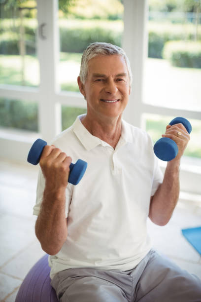 istock Senior man exercising with dumbells at home 645044642
