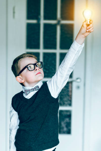 istock Boy holds glowing light bulb in the air and gets and idea 645056130
