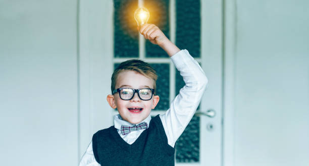 istock Boy gets a great idea while holding glowing light blub over his head 645056138
