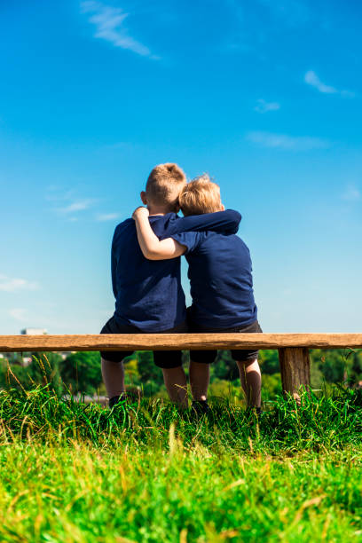 istock Two friends hug each other while sitting on a bench outside 645057338
