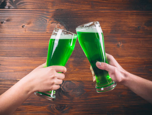 istock St Patrick's Day concept two mug on hands green beer against wooden background 645060802