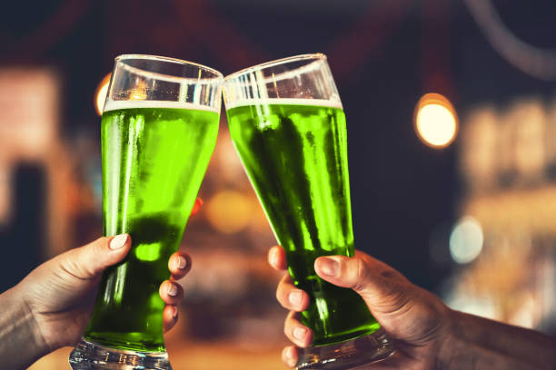 Two friends toasting with glasses of green beer at the pub with free space for your text. Beautiful background of the Beer Fest and St. Patrick's day. fine grain. Soft focus. Shallow DOF stock photo