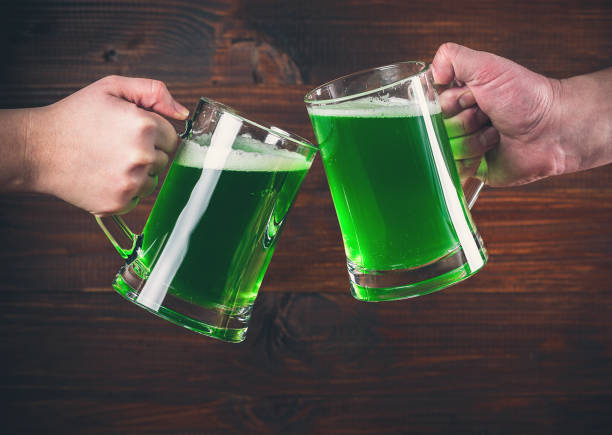 istock St Patrick's Day concept two mug on hands green beer against wooden background 645060882