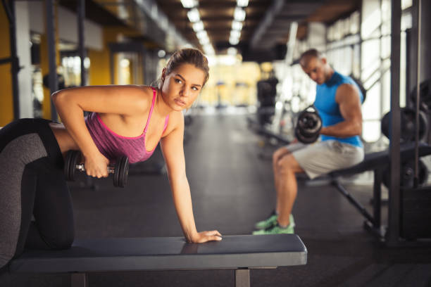 istock Young woman having weight training with dumbbells at gym 645083748