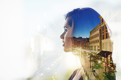 Multiple exposure shot of young businesswoman superimposed over a cityscape
