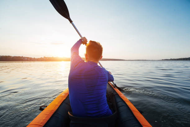 istock man floating on lake in a kayak at fantastic sunset. 645086010