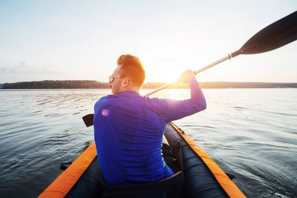 istock man floating on lake in a kayak at fantastic sunset. 645086078