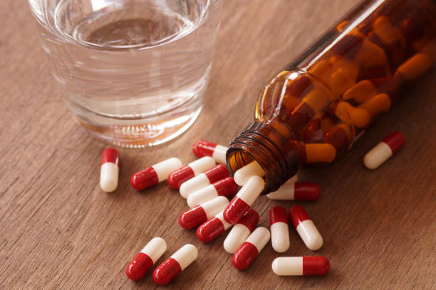 istock capsule and glass on bottle pouring on wood table 645086088