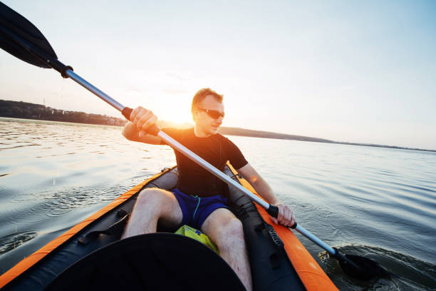 istock man floating on lake in a kayak at fantastic sunset. 645086190