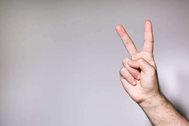 istock Man's hand doing victory V sign a white background 645086472