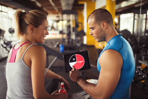 istock Young woman discussing workout progress with fitness instructor 645089094