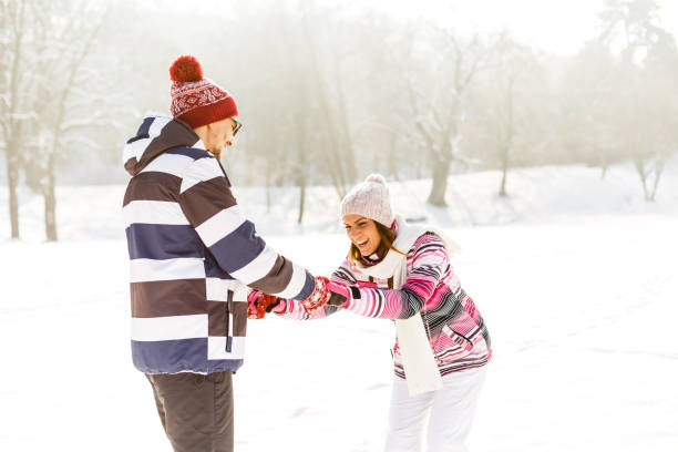 istock Playful couple holding hands on snow 645092328