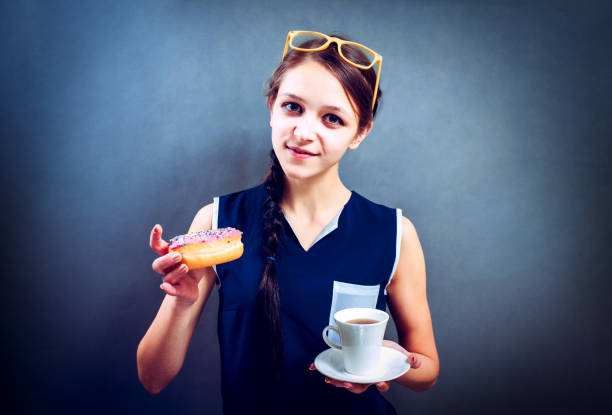 istock Cheerful lady in  T-shirt eating a donut and drinking coffee 645095536