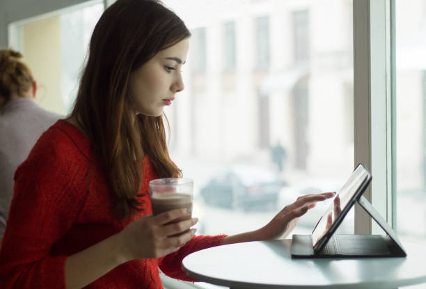 istock Young girl looking at tablet in cafe with big window 645104772