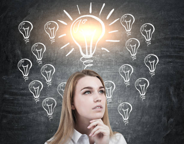 istock Pensive blond woman and shining light bulb 645111978