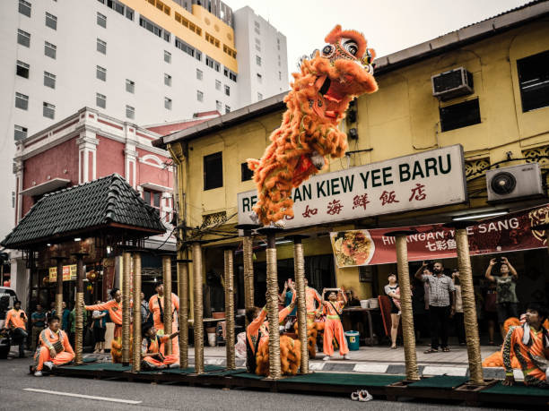 A troupe of lion dancers is performing at the street during the Chinese New Year in front of a restaurant. During this festivity groups of Lion dancers perform  in front of business and shops for a monetary reward. It brings good luck to the owners of the business.