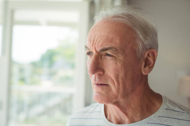 istock Thoughtful senior man standing next to window 645117246