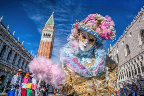 Venice, Italy- February 4, 2016. Venetian costumes pose on St. Mark square during the Venice Carnival days. The most  famous festival in the world. Venetian costumes pose on St. Mark square during the Venice Carnival days. The most  famous festival in the world. gondola traditional boat photos stock pictures, royalty-free photos & images