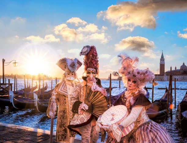 venezia, italia- 12 febbraio 2016. i costumi veneziani posano davanti alle gondole durante i giorni del carnevale di venezia. il festival più famoso del mondo. - carnival mask women party foto e immagini stock