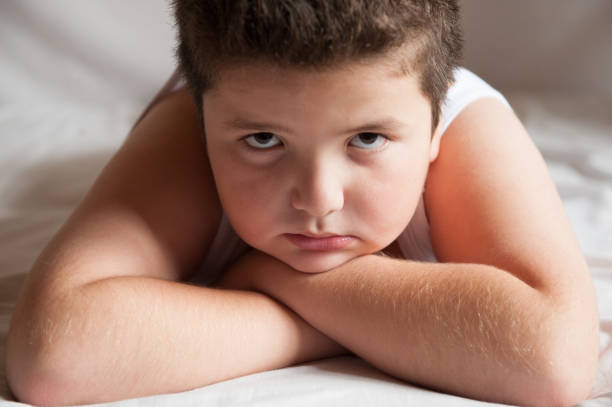 istock serious cute fat boy is lying and looking into camera 645135686