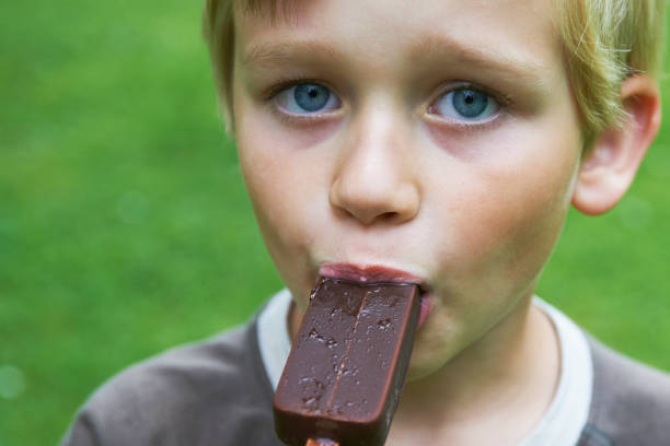 istock Child blond boy eating a tasty ice cream outside 645138080