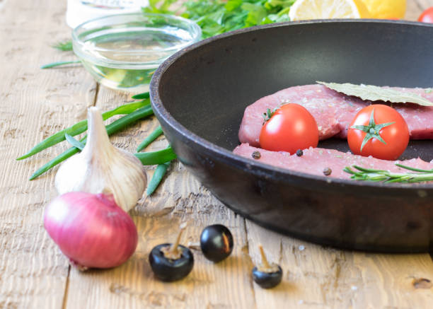 istock Raw pork on a frying pan on a rustic table. 645138312