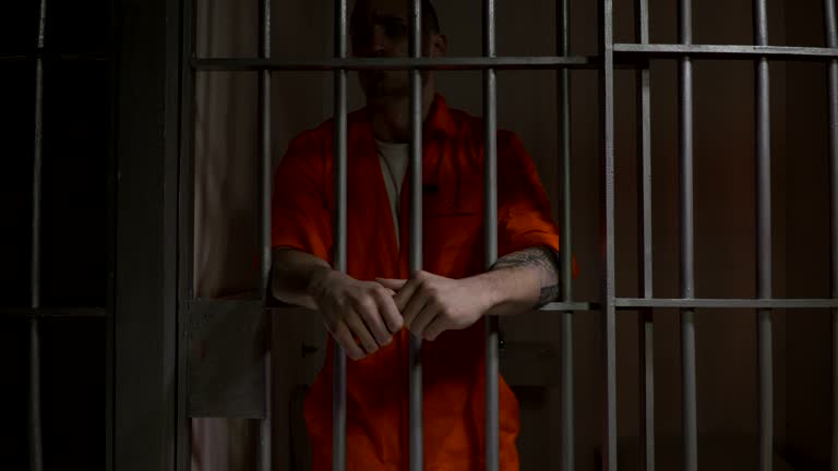 4K Male Prisoner in Jail Cell leaning on the bars