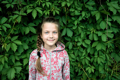 portrait of smiling child girl in green hop leaves