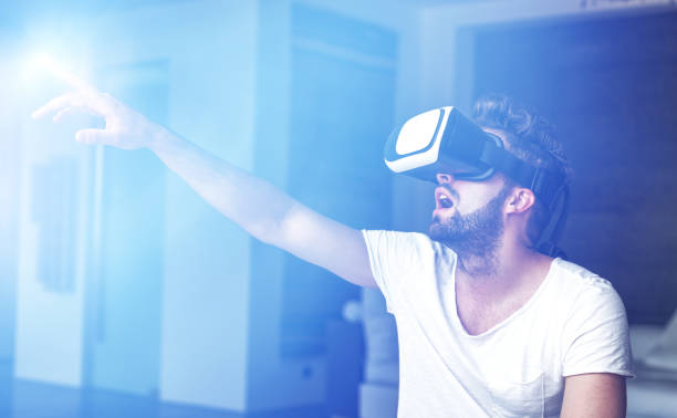 istock Young man with VR glasses playing virtual reality 645153714