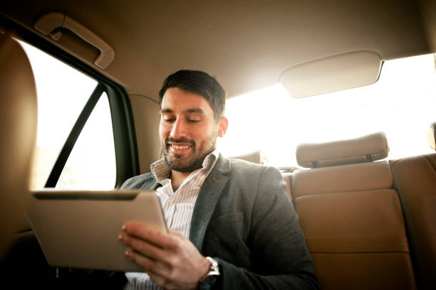 Business on the move Handsome Young Businessman Using Digital Tablet in Car car portrait men expertise stock pictures, royalty-free photos & images