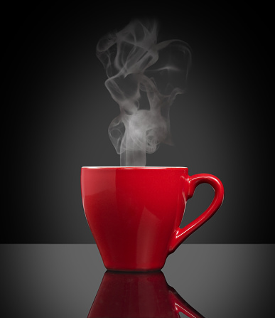 red cup of steamy coffee on a mirror isolated on black background