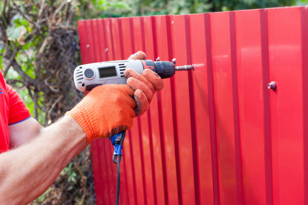 istock Metal fence installation. Work man in gloves with a drill 645170174