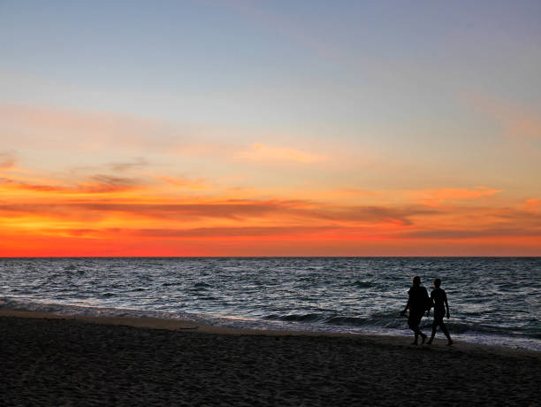 istock Silhouette couple walking along sunset beach 645177042