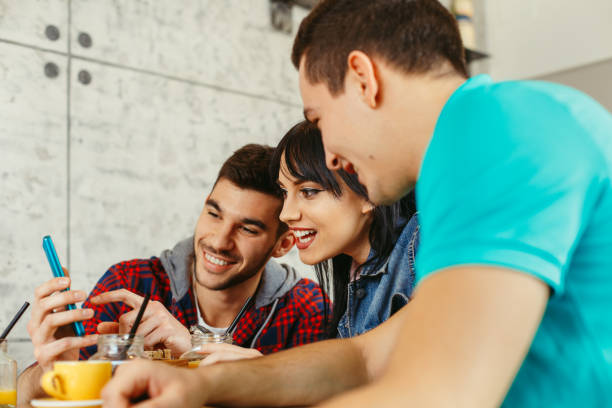 istock Group of young people having fun in cafe via smartphone 645210230