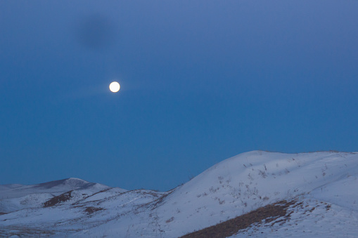 The moon against the background of snow mountains and the blue sky.