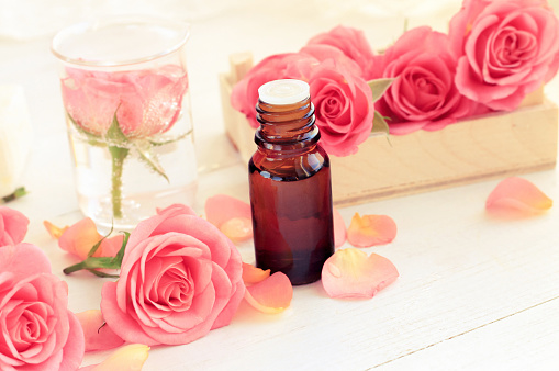 Rosa flores frescas de rosa y pétalos, aceite esencial en botella de vidrio oscuro. photo