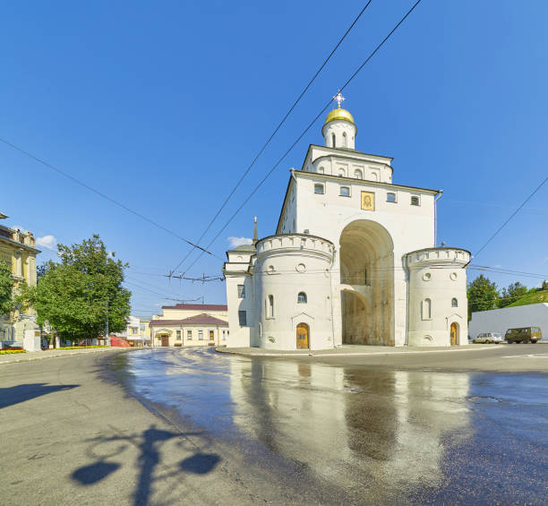 Wide angle view of the Golden Gate in Vladimir, Russia, reflecting in wet asphalt road under blue sky A wide angle view of the famous Golden Gate entrance in Vladimir, Russia, reflecting in wet asphalt road under blue sky in summer. vladimir russia stock pictures, royalty-free photos & images