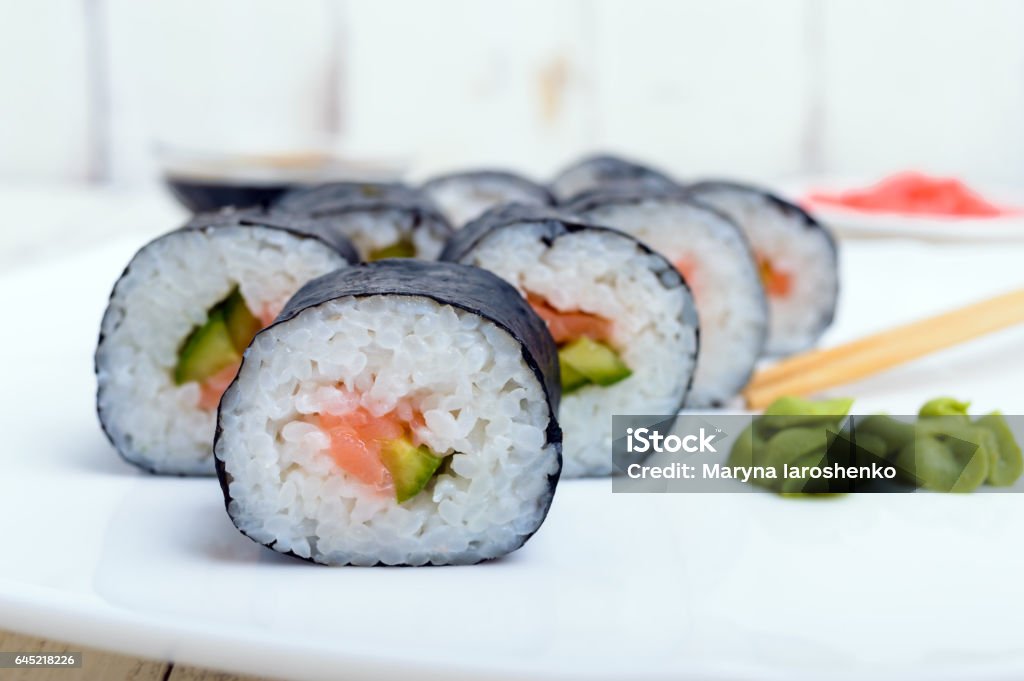 Traditional eastern dish with salmon sushi rolls on a white plate. Traditional eastern dish with salmon sushi rolls on a white plate. Close-up. Appetizer Stock Photo